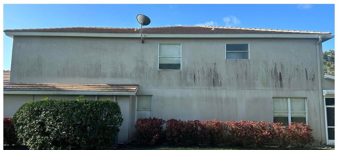Before: a two-storey stucco home streaked with algae and rust stains in Southwest Florida — Gulf Coast Sealing & Pressure Cleaning