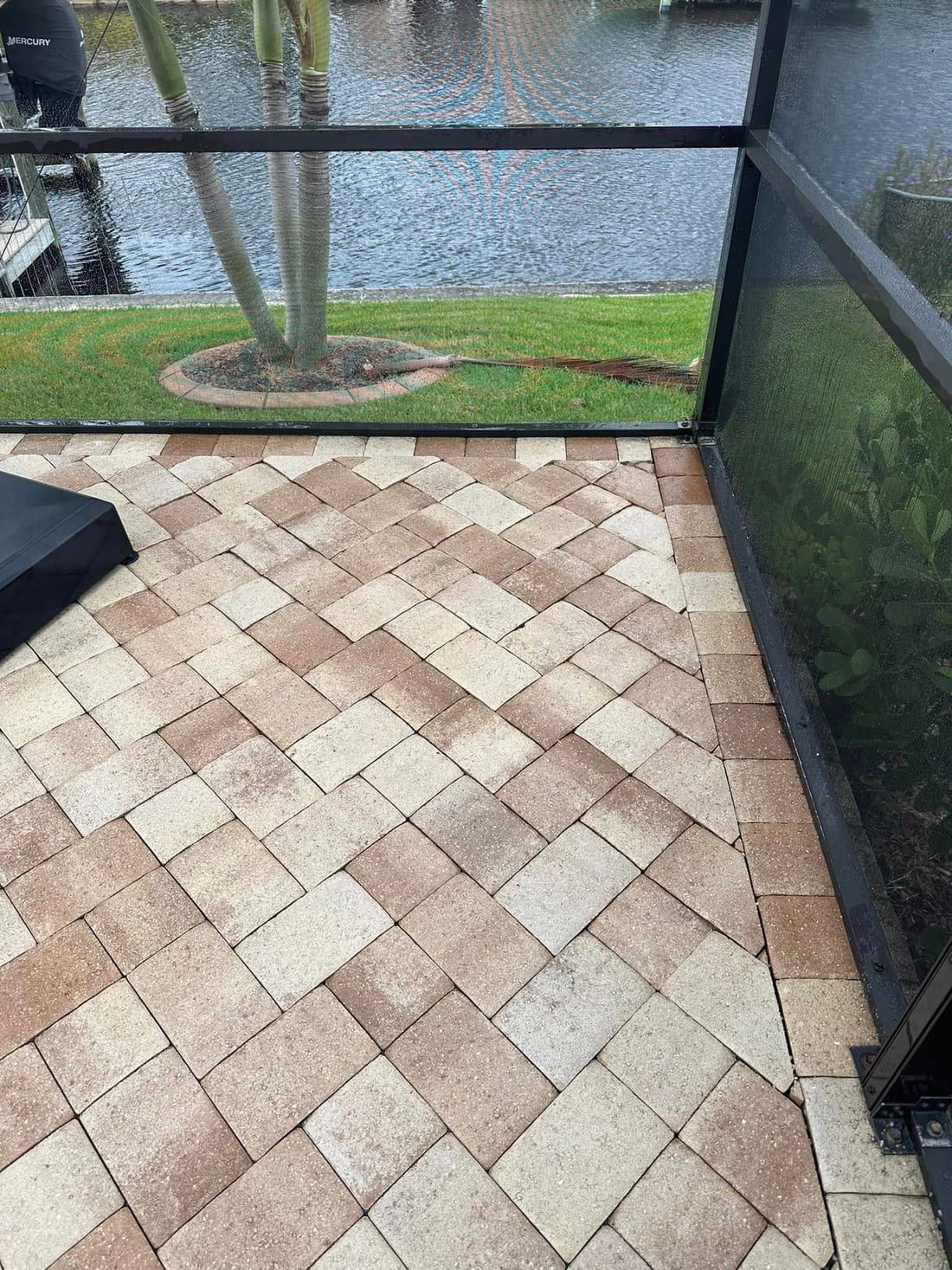 After: the same lanai section re-laid level with the sand swept in, by the canal, in Southwest Florida — Gulf Coast Sealing & Pressure Cleaning