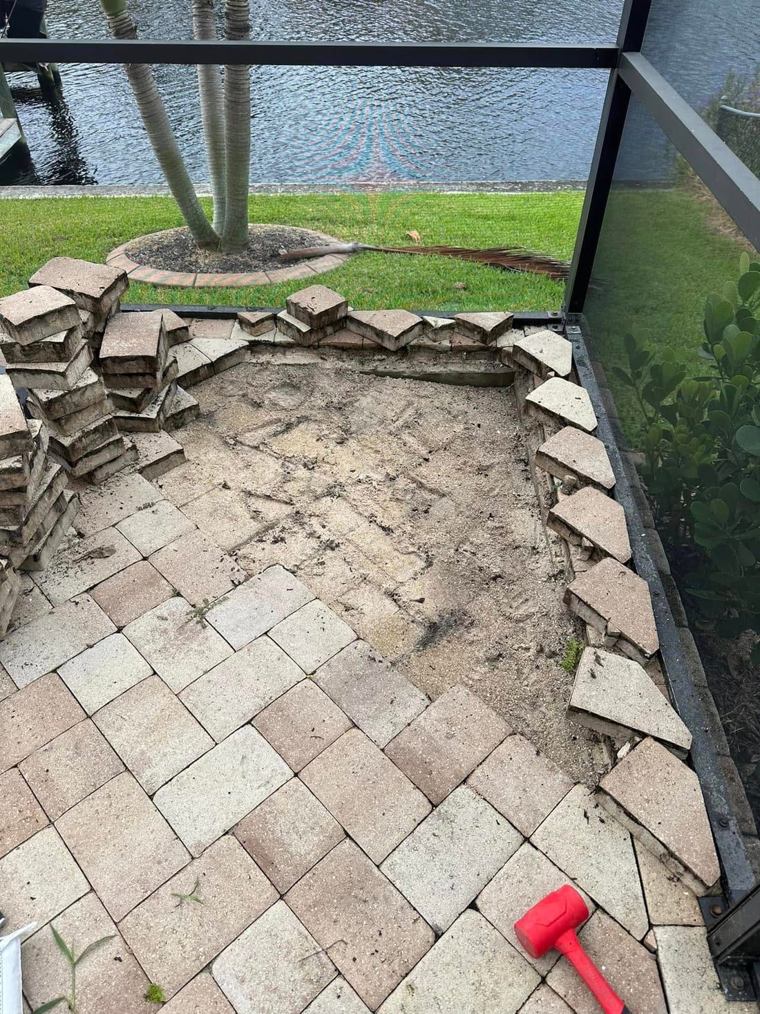 Before: a sunken lanai paver section lifted out and stacked, ready to be re-based, in Southwest Florida — Gulf Coast Sealing & Pressure Cleaning