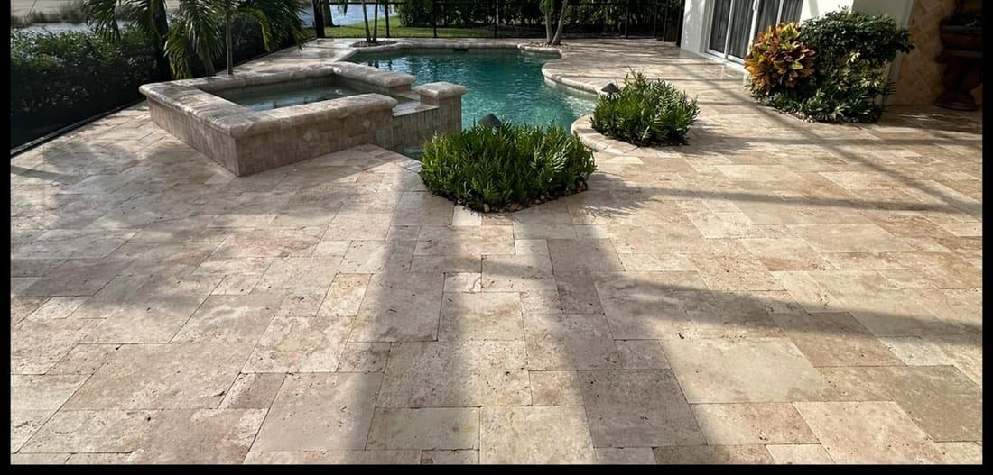 After: the same travertine deck cleaned and sealed, the stone color warmer and deeper, in Naples, FL — Gulf Coast Sealing & Pressure Cleaning