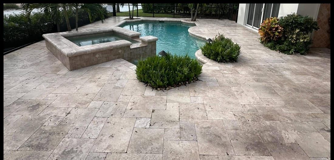 Before: a pale, flat-looking travertine pool deck and spa in Naples, FL — Gulf Coast Sealing & Pressure Cleaning