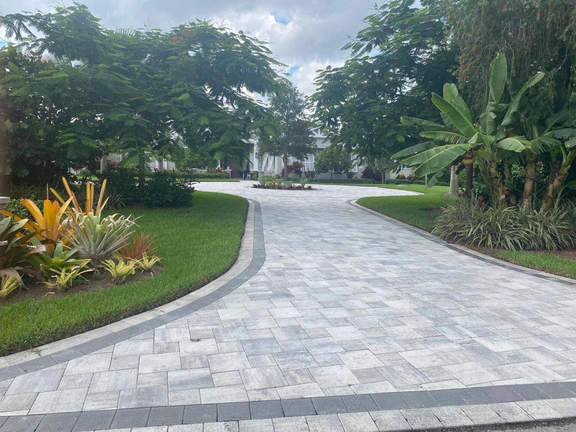 Newly installed brick paver driveway with fresh landscaping in Bonita Springs, FL — Gulf Coast Sealing & Pressure Cleaning