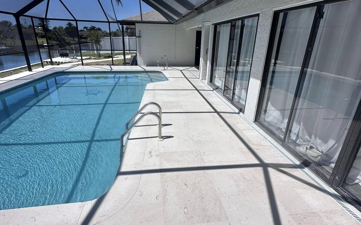 New travertine pool deck and lanai installed under a screen cage in Bonita Springs, FL — Gulf Coast Sealing & Pressure Cleaning
