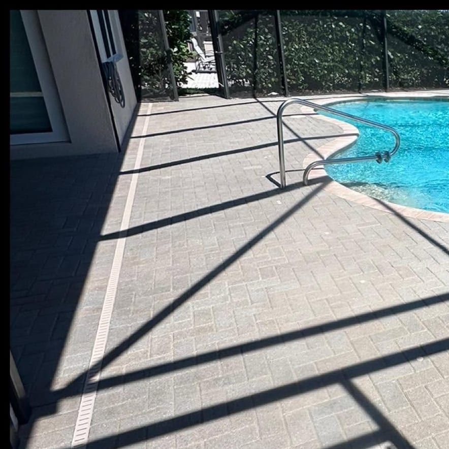 Screened pool deck with freshly sealed pavers running to the water line in Bonita Springs, FL — Gulf Coast Sealing & Pressure Cleaning